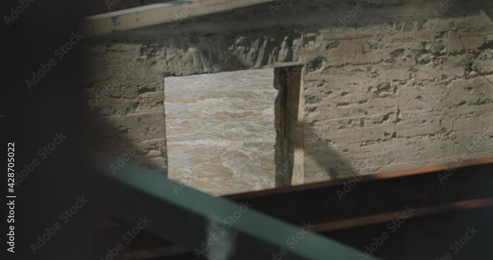 View of the river water through a window of a abandoned heritage industrial power generation building on Chaudière Island sits with steel beams supporting the exterior stone structure. View of the river water through a window of a abandoned heritage industrial power generation building on Chaudière Island sits with steel beams supporting the exterior stone structure.