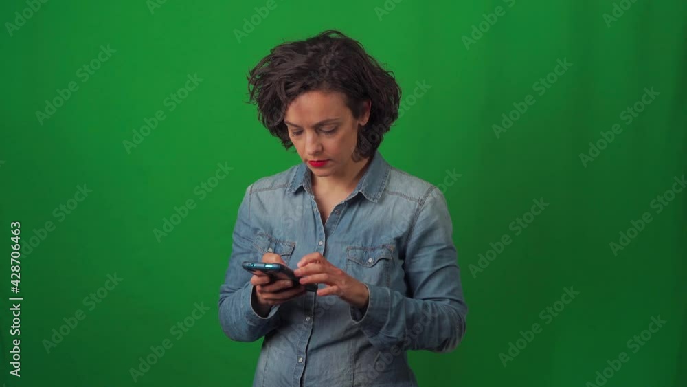 Caucasian woman on green chroma background, with very marked gestures. Writing on cell phone and sending a message or sms. Caucasian woman on green chroma background, with very marked gestures. Writing on cell phone and sending a message or sms.
