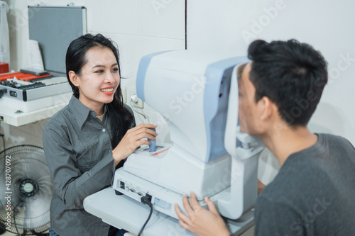 a female doctor and a male patient doing an eye check using a device at an eye clinic