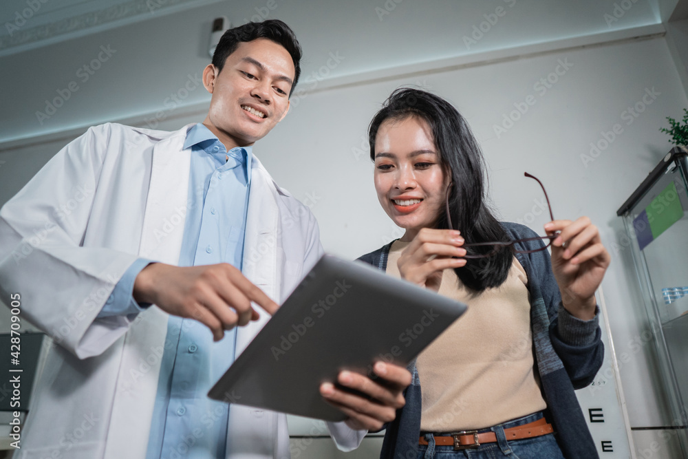 A male doctor is giving the results of an analysis to a female patient who has had an eye exam at an eye clinic A male doctor is giving the results of an analysis to a female patient who has had an eye exam at an eye clinic