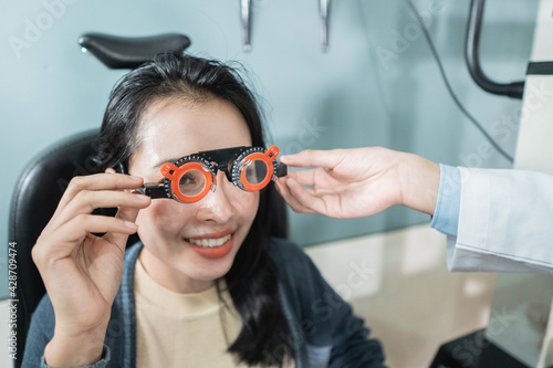 a doctor is using measuring glasses to a female patient in a room at an eye clinic