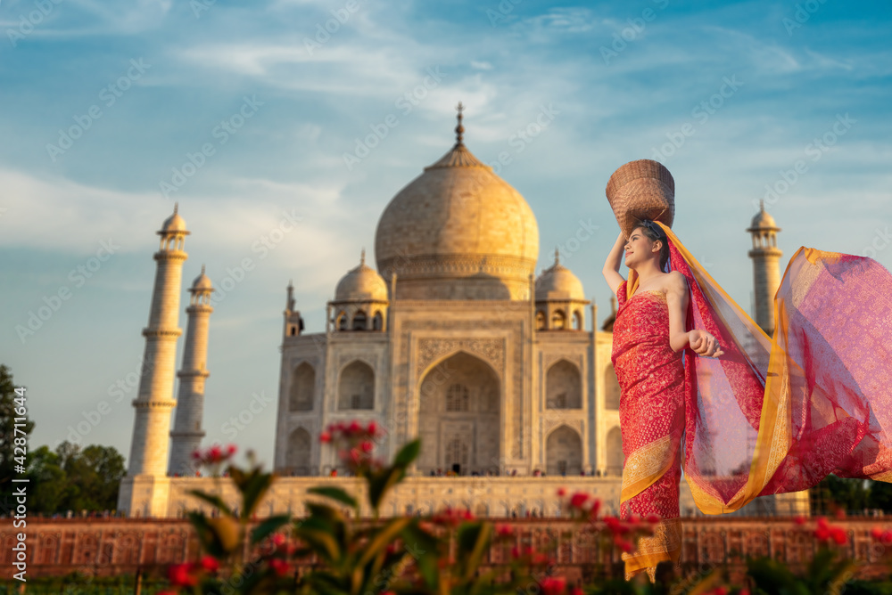 Fototapeta premium Asian beautiful girl wearing Indian traditional cloth with Taj Mahal land mark ivory-white marble building mosque, Agra India .