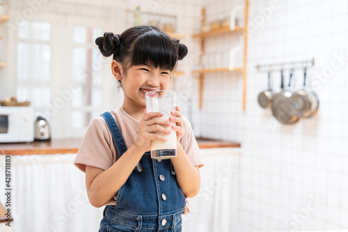 Asian little young girl drinking milk in the kitchen with smiling face photo