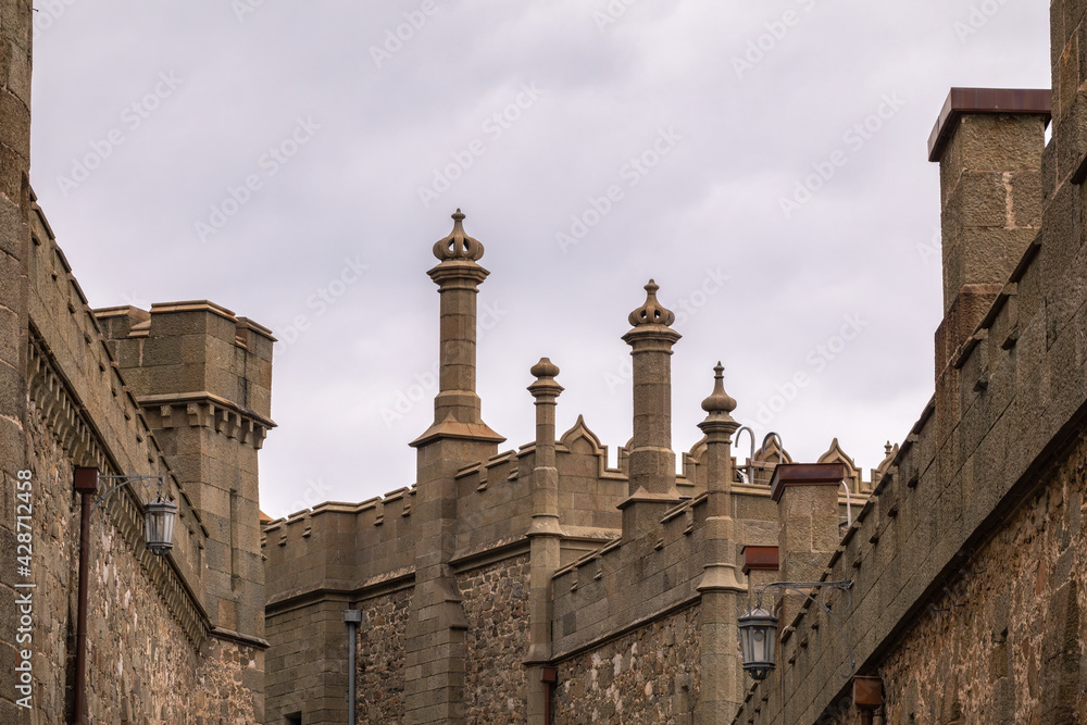 The walls and towers of the old palace on the background of a cloudy sky