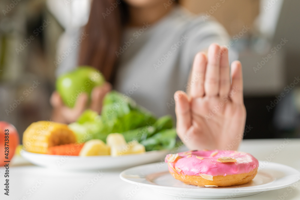 Diet, Dieting young asian woman or girl use hand push out, deny sweet donut and choose green apple, salad vegetables, eat food for good healthy, health when hungry. Close up female weight loss person. Diet, Dieting young asian woman or girl use hand push out, deny sweet donut and choose green apple, salad vegetables, eat food for good healthy, health when hungry. Close up female weight loss person.