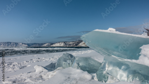 Obraz na plátně Turquoise ice hummocks on the snow-covered shore