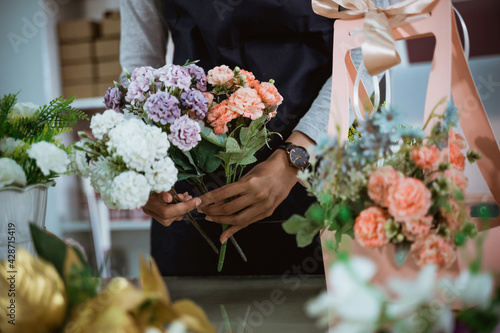 Fotografi portrait florist preparing a gift flower on table workspace for customer