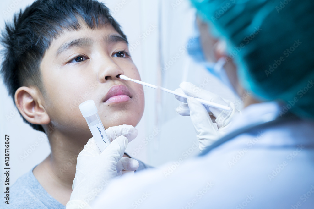 Doctor taking a swab for corona virus from potentially infected Asian boy nose.Covid-19 laboratory test.Medical staff with PPE suit test coronavirus covid-19 to asian kid by nose swab at hospital. Doctor taking a swab for corona virus from potentially infected Asian boy nose.Covid-19 laboratory test.Medical staff with PPE suit test coronavirus covid-19 to asian kid by nose swab at hospital.