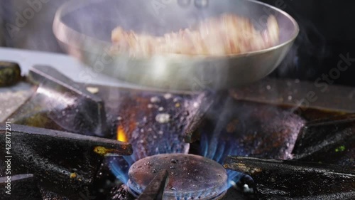 Making fried pork Brasso style - frying the pork meat strips in a pan, tossing and turning them photo