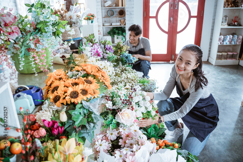 happy young couple wearing apron checking condition flower working in flower shop