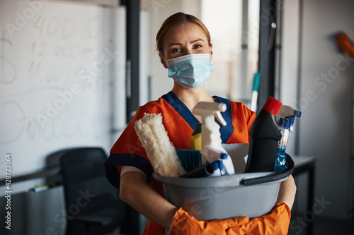 Cleaner in a face mask showing her cleaning products photo