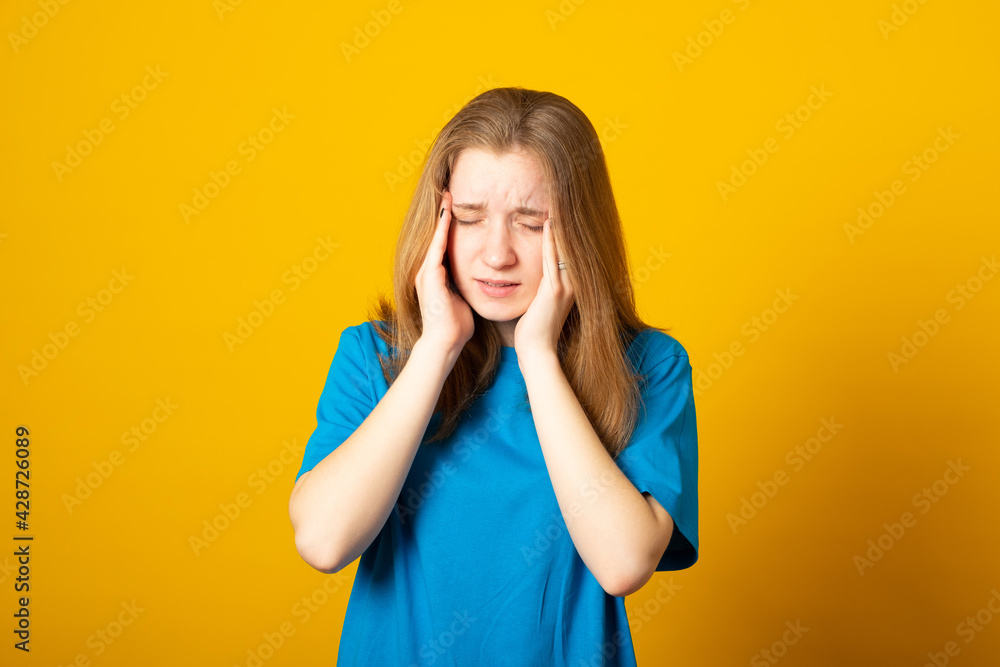 Young blonde girl wearing casual blue t-shirt over isolated background suffering from headache desperate and stressed because pain and migraine. Hands on head. Young blonde girl wearing casual blue t-shirt over isolated background suffering from headache desperate and stressed because pain and migraine. Hands on head.