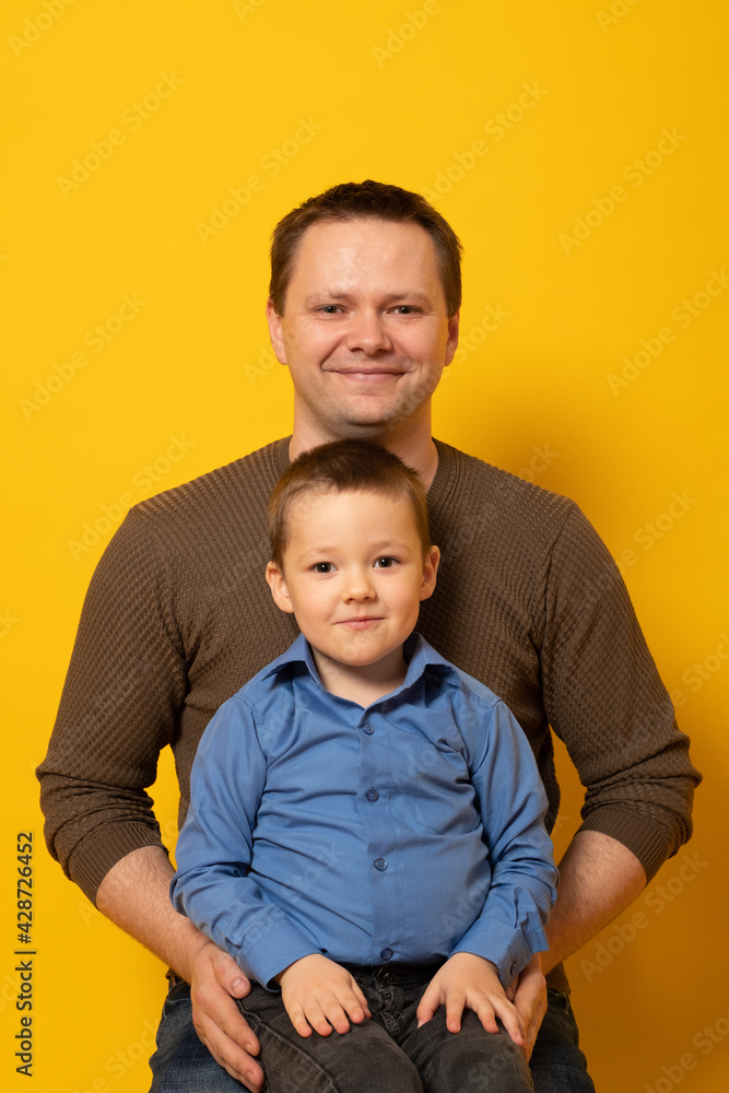 Happy father's day! cute dad and son hugging on colored yellow background. Happy father's day! cute dad and son hugging on colored yellow background.