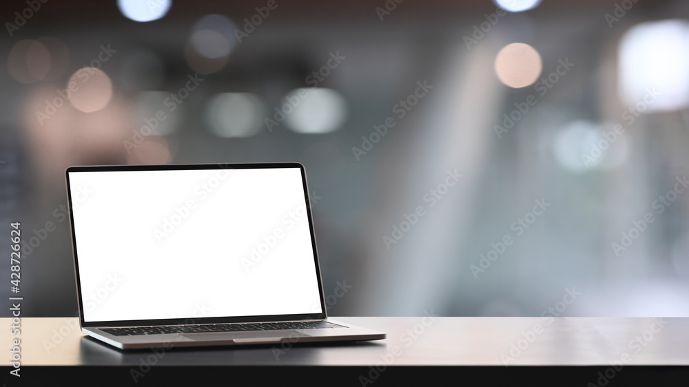 Mock up computer laptop with blank screen on wooden table and blurred office interior background. Mock up computer laptop with blank screen on wooden table and blurred office interior background.