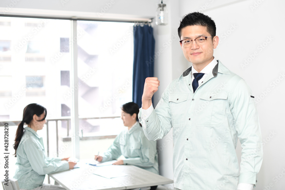 ガッツポーズをする作業着を着た若い男性 ガッツポーズをする作業着を着た若い男性