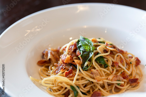 Spicy spaghetti with fried bacon. Spaghetti with fried crispy bacon and chili fried basil leave.