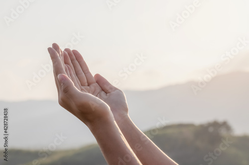 Human hands praying to god on mountain sunset background © AungMyo