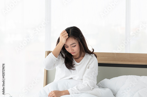 Beautiful Asian woman waking up in her bed, stretching and smiling. Woman sitting on the bed and stretch herself in the morning. Asian female stretching in bed after wake up in the morning.