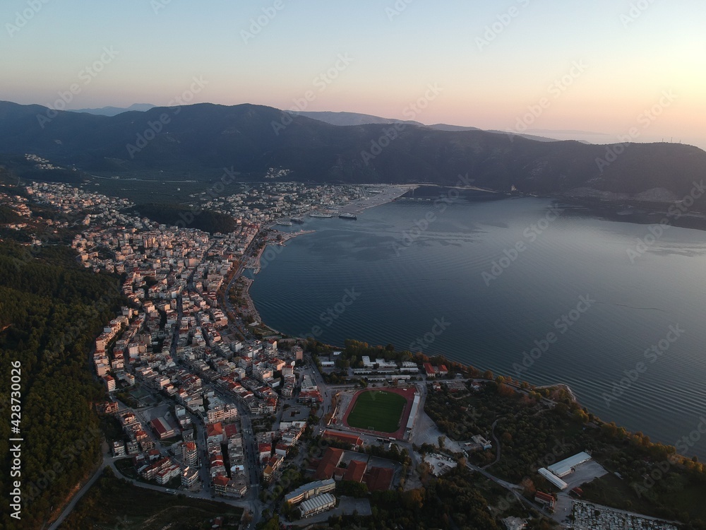 Aerial Photo Of Igoumenitsa city Buildings, Port And Ferryboats To Corfu Island And Italy During Sundown. Thesprotia, Epirus, Greece.