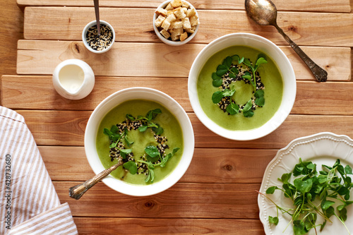 broccoli puree soup with sesame seeds, croutons and herbs. wooden background, top view