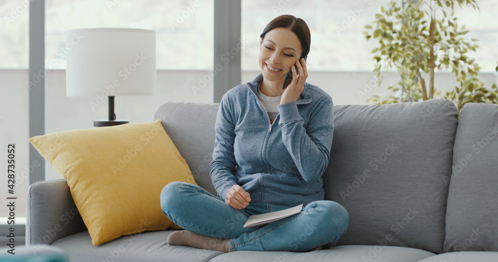 Smiling woman at home talking with her smartphone