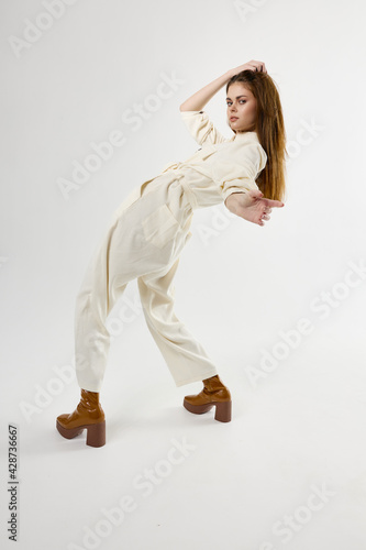 woman in suit trendy shoes bent over back light background