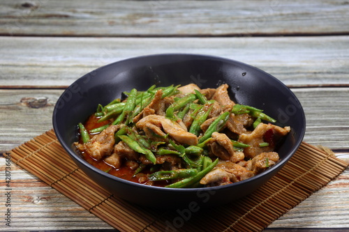 Traditional fried string bean and chopped chicken thigh mixed red curry paste serving on the plate. Famous hot and spicy food in Asia restaurant. 