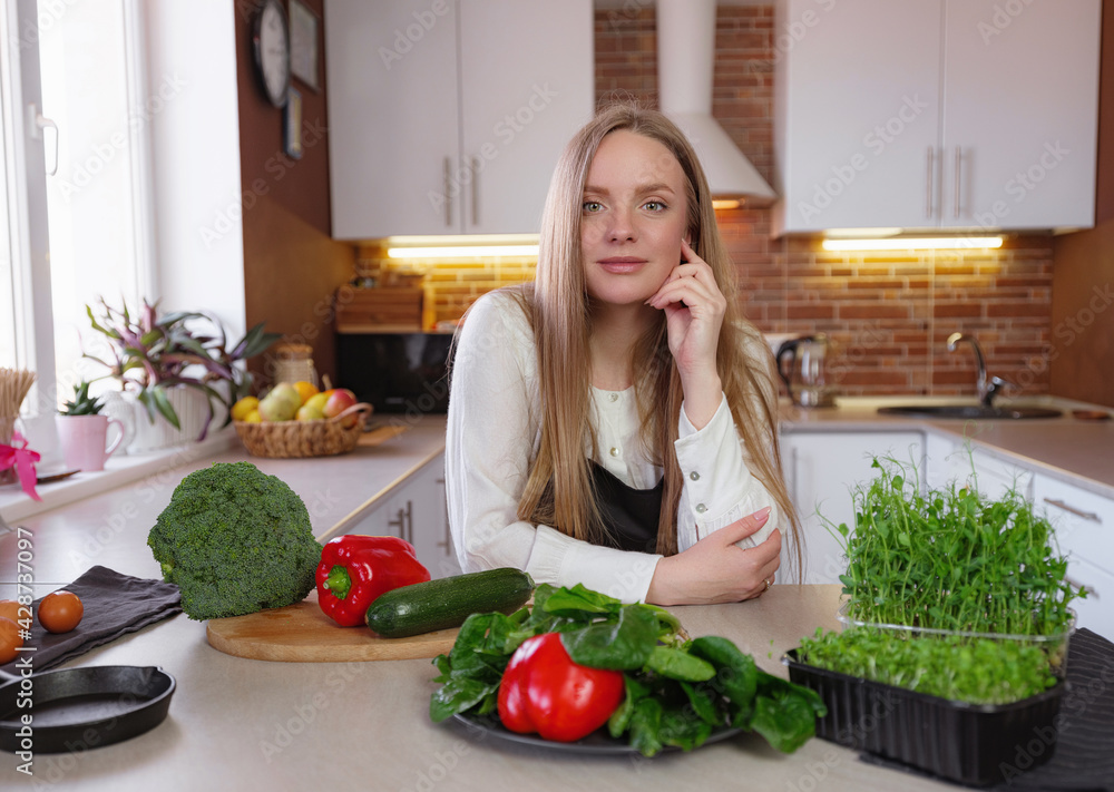 A young happy lady standing in the kitchen while cooking. A young happy lady standing in the kitchen while cooking.