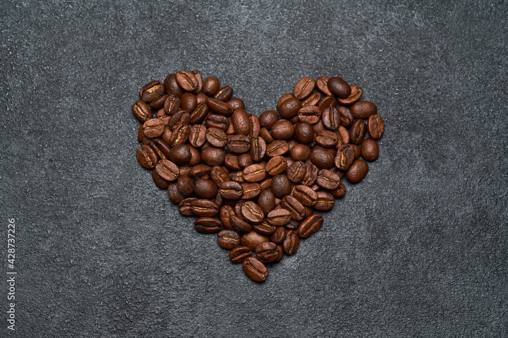 Heart shaped roasted coffee beans on dark concrete background Heart shaped roasted coffee beans on dark concrete background