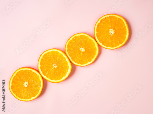 Diagonal line of orange circles on pink background. Orange slices border with copy space. Free space for text or product. Flat lay, top view.