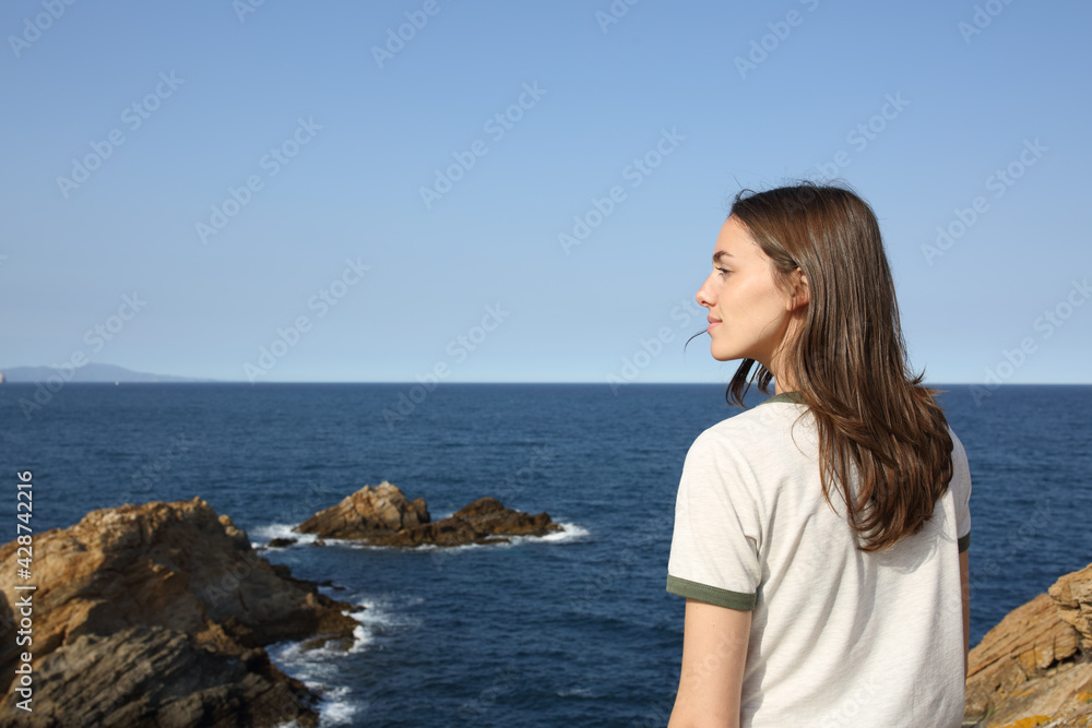 Woman standing contemplating views on the beach