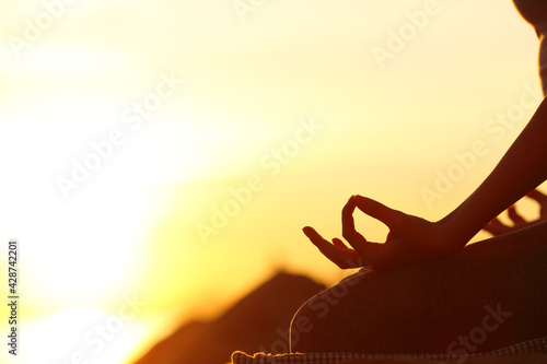 Woman hand silhouette doing yoga at sunset