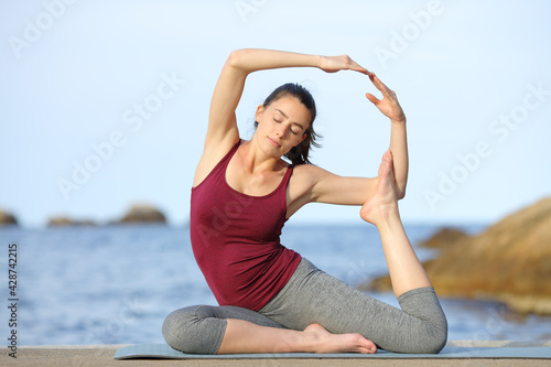 Woman practicing yoga poses on the beach