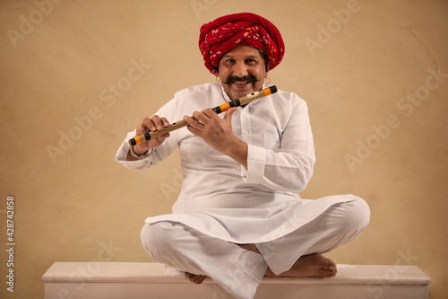 A HAPPY TURBANED MAN SITTING WITH HIS FLUTE TO PLAY	 photo