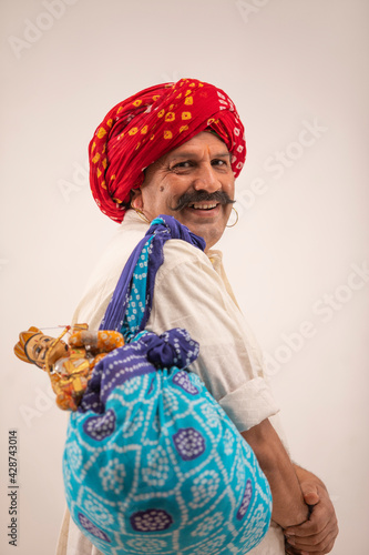 A RURAL KATHPUTLI ARTIST TURNING AROUND AND SMILING AT CAMERA	 photo