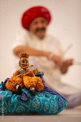 CLOSE SHOT OF A HANDMADE TRADITIONAL PUPPET WITH THE ARTIST IN BACKGROUND	 photo