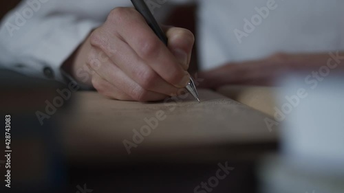 Closeup view of female hand making notes, writing letter in vintage sketchbook notebook diary. Education concept woman sits at desk, studies. Books lay on table. Keep diary of memories. Handwriting