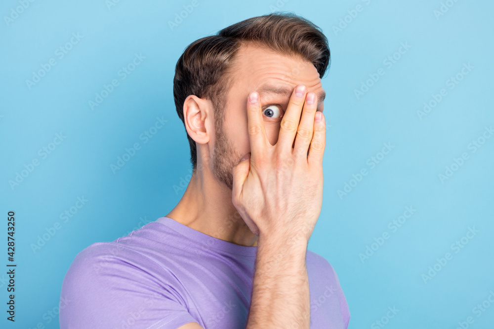 Photo of scared blond hair guy hide wear purple t-shirt isolated on light blue color background Photo of scared blond hair guy hide wear purple t-shirt isolated on light blue color background