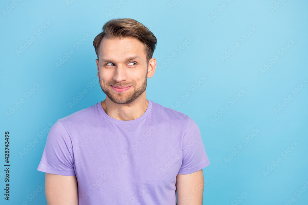 Obraz premium Portrait of funky optimistic blond hair guy look empty space wear purple t-shirt isolated on light blue color background