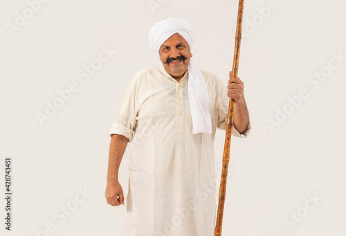 AN ADULT MAN HAPPILY STANDING WITH STICK IN HAND IN FRONT OF CAMERA	 photo
