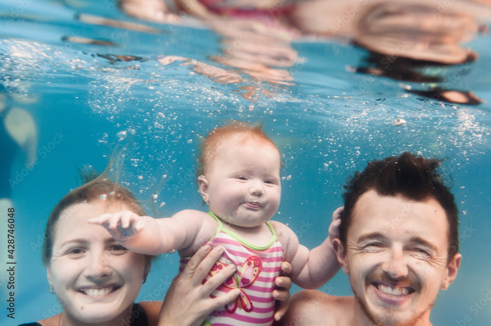 Mother, father with daughter learn to swim on swimming lesson, doing