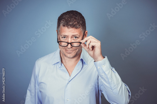 businessman with black glasses and blue shirt posing against blue background in the studio