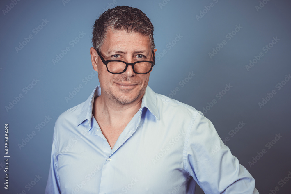 businessman with black glasses and blue shirt posing against blue background in the studio businessman with black glasses and blue shirt posing against blue background in the studio