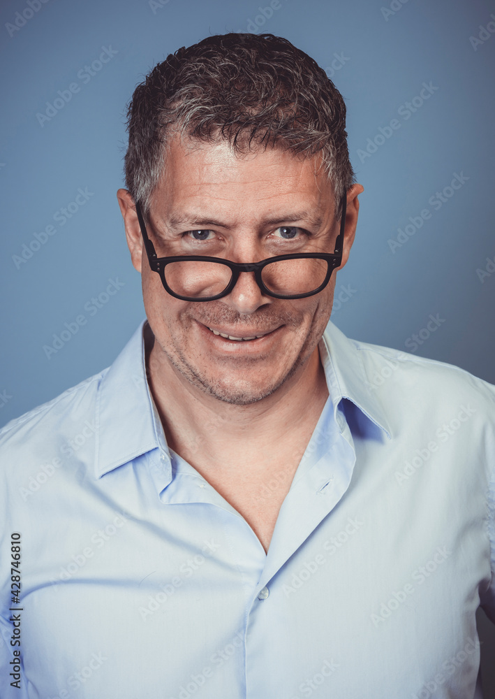 businessman with black glasses and blue shirt posing against blue background in the studio businessman with black glasses and blue shirt posing against blue background in the studio