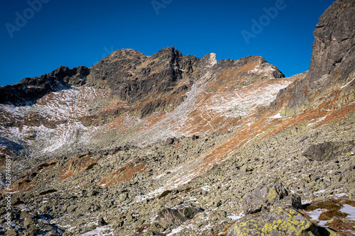 Rocky slope of High Tatra Mountain peaks and crags. The trail to Zawrat pass. An old path to Świnica Peak can be seen in the distance. Selective focus on the rocks, blurred background.