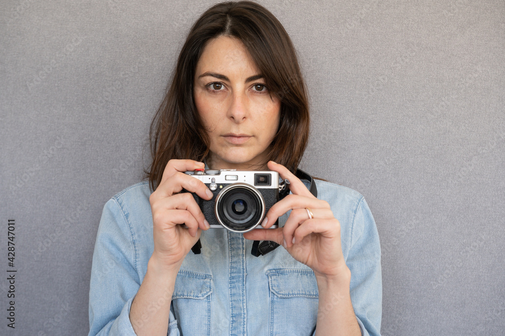 Front view of portrait of nice and serious young woman holding a vintage style camera Front view of portrait of nice and serious young woman holding a vintage style camera