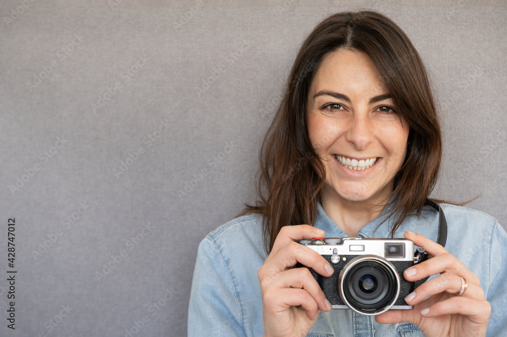 Front view of portrait of lovely young woman, happy and very smiling, holding a retro style camera. Front view of portrait of lovely young woman, happy and very smiling, holding a retro style camera.