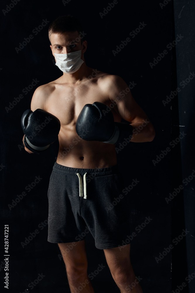 sporty man in medical mask and in boxing gloves on black background shorts fitness model sporty man in medical mask and in boxing gloves on black background shorts fitness model