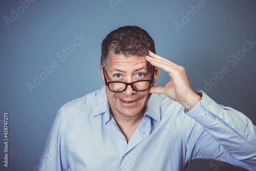 Wallpaper Mural businessman with black glasses and blue shirt posing against blue background in the studio Torontodigital.ca
