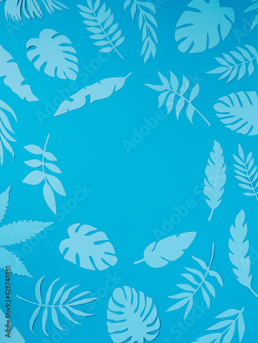 Natural tropical frame with blue paper palm leaves on pastel blue background. Minimal summer exotic texture concept with copy space for text. Flat lay, top view. © Aleksandar